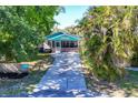 Charming cottage exterior with screened-in porch, driveway and lush tropical landscaping at 140 Avenida De La Isla, Nokomis, FL 34275