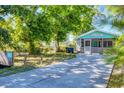Charming cottage exterior with screened-in porch, lush landscaping, and long driveway at 140 Avenida De La Isla, Nokomis, FL 34275