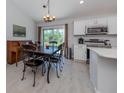 Bright eat-in kitchen features a dark wood dining table, stainless appliances, and backyard access at 15232 Faulkner Ave, Port Charlotte, FL 33953