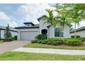 Attractive single-story home with a brick driveway, mature palm trees, and neat landscaping at 1565 Hyssop Loop, North Port, FL 34289