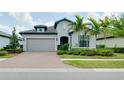 Inviting single-story home with a brick driveway, well-maintained landscaping, and a neutral color scheme at 1565 Hyssop Loop, North Port, FL 34289