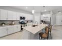 Bright kitchen features white cabinets, stainless steel appliances, and a large island with bar seating at 1608 Saddlewood Cir, Port Charlotte, FL 33953