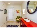 Bright foyer with neutral tiled floors, vibrant accent furniture, art and a decorative round mirror at 1711 Gondola Park Dr # 1711, Venice, FL 34292