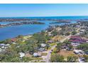 A scenic aerial view showing several homes, lush trees, and blue water in the background on a sunny day at 203 Palm Ave, Nokomis, FL 34275