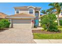 Charming two-story home featuring a paved driveway, attached garage, and a bright blue front door at 2197 Mesic Hammock Way, Venice, FL 34292