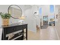 Bright foyer featuring a round mirror, console table, and stairway to an open floorplan at 2197 Mesic Hammock Way, Venice, FL 34292