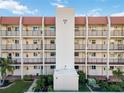 Condominium building with multiple floors with balconies and a red tile roof, surrounded by green landscaping and palm trees at 230 Santa Maria St # 333, Venice, FL 34285