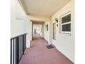 Exterior hallway leading to unit 333, featuring neutral paint, a black railing, and exterior windows with blinds at 230 Santa Maria St # 333, Venice, FL 34285