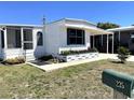 Quaint single-story home with a covered carport, screened porch, and manicured landscaping at 235 Trailorama Dr, North Port, FL 34287