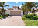A charming home showcasing a well-manicured lawn, paver driveway, and two-car garage at 24153 Spartina Dr, Venice, FL 34293