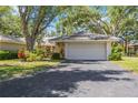 Charming home with a paved driveway leading to an attached garage, surrounded by lush landscaping and mature trees at 269 Southampton Dr # 303, Venice, FL 34293