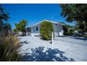 Spacious driveway and side yard with electric car charger and mature landscaping at 271 Manor Rd, Venice, FL 34293