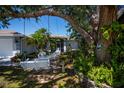 Relaxing front yard featuring a porch swing, patio furniture, and lush landscaping at 271 Manor Rd, Venice, FL 34293