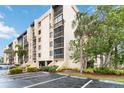 Condominium complex exterior featuring beige siding, a parking lot, tropical landscaping, and a blue sky at 3006 Caring Way # 304, Port Charlotte, FL 33952