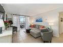 Bright living room features neutral decor, tile flooring, comfortable seating, and sliding glass doors to balcony at 3006 Caring Way # 304, Port Charlotte, FL 33952