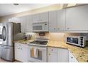 Well-lit kitchen with stainless steel refrigerator, white cabinetry, granite countertops and modern appliances at 414 Laurel Lake Dr # 203, Venice, FL 34292