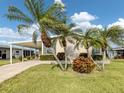 Inviting home with a well-manicured lawn, mature palm trees, and covered carport at 423 Pirates Pt, North Port, FL 34287