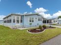 A charming home with light blue siding, complemented by a well-kept lawn and a welcoming sunroom at 443 Landsedge Dr, North Port, FL 34287