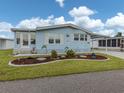 A cozy residence featuring light blue siding, a lush green lawn, and meticulous landscaping at 443 Landsedge Dr, North Port, FL 34287