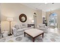 Bright living room featuring neutral furniture, a large round mirror, and a view into the entryway, enhancing the cozy feel at 4641 Gaeta Dr, Venice, FL 34293