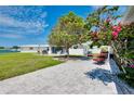 Spacious backyard with a stone patio, lush lawn, and mature trees, ideal for outdoor entertaining at 553 Circlewood Dr # T11, Venice, FL 34293