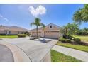 Spacious driveway leading to a three-car garage with mature palm trees and manicured landscaping at 5641 Hidden Oak Ct, North Port, FL 34287
