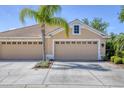 A tan home with a tile roof and a three-car garage surrounded by lush landscaping at 5641 Hidden Oak Ct, North Port, FL 34287