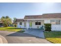 The house has a white exterior, brown roof, covered parking, green lawn, and clear blue sky at 680 Circlewood Dr # W3, Venice, FL 34293