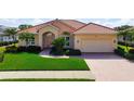 Charming single-story home featuring a red tile roof, paver driveway, and lush green landscaping at 744 Fringed Orchid Trl, Venice, FL 34293