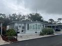 Quaint mobile home with light gray exterior, decorative shrubs, and plenty of windows for natural light at 795 Cervina N Dr, Venice, FL 34285