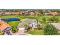 Stunning home on golf course with water view, features a lush green lawn, mature trees, and a circular driveway at 854 Blue Crane Dr, Venice, FL 34285