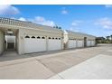 Exterior view of multiple garages featuring white doors and matching roof in a sunny neighborhood at 930 Capri Isles Blvd # 120, Venice, FL 34292