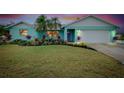 Charming single-story home with colorful landscaping, palm trees, and an attached two-car garage at dusk at 990 Sea Fox Rd, Venice, FL 34293