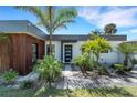 Modern home featuring a stylish exterior with wood accents, landscaping and well-maintained lawn at 106 Playmore Dr, Venice, FL 34293