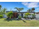 Modern home featuring a stylish exterior with wood accents, landscaping and well-maintained lawn at 106 Playmore Dr, Venice, FL 34293
