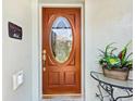 Inviting front door featuring a decorative oval glass insert, complemented by a welcome sign and potted plant at 11343 Bertolini Dr, Venice, FL 34292