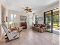 Bright living room with tile flooring, fireplace, ceiling fan, and sliding glass doors to the lanai at 11343 Bertolini Dr, Venice, FL 34292