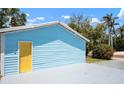 A light blue garage features a yellow door, a spacious concrete driveway and a neatly landscaped yard at 121 Dolly St, Punta Gorda, FL 33950