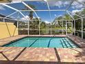 Relaxing screened-in pool area with brick pavers and a clear view of the lush backyard and calm lake at 13150 Huerta St, Venice, FL 34293
