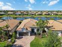 Beautiful aerial view of a home with a tile roof near a scenic lake in a tranquil neighborhood at 13872 Rinuccio St, Venice, FL 34293