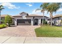 Charming single-story home featuring a well-manicured lawn, paver driveway, and two-car garage at 13872 Rinuccio St, Venice, FL 34293
