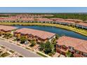 Scenic aerial view of townhome community beside a lake surrounded by greenery and other residences at 20237 Lagente Cir, Venice, FL 34293