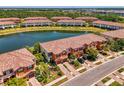 Aerial view of townhomes with a lake, lush landscaping, and private driveways in a well-maintained community at 20237 Lagente Cir, Venice, FL 34293