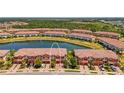 Aerial view of townhomes overlooking a tranquil lake surrounded by lush landscaping and mature trees at 20237 Lagente Cir, Venice, FL 34293