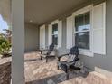 Relaxing front porch features a pair of adirondack chairs and stylish brick pavers at 20285 Symphony Pl, Venice, FL 34293