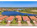 Aerial view of homes with terracotta roofs surrounding a beautiful lake and nature preserve at 23494 Copperleaf Dr, Venice, FL 34293