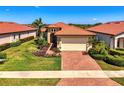 Home exterior featuring a terracotta roof, lush landscaping, and brick paver driveway at 23494 Copperleaf Dr, Venice, FL 34293