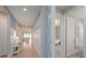 Bright hallway with light wood floors, decorative wainscoting and views into the living space and a bedroom at 264 Caserta Ct, Nokomis, FL 34275