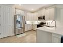 Modern kitchen with white cabinets, stainless steel appliances, and tile flooring at 268 Ibiza Loop, Venice, FL 34292
