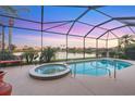 Screened-in pool and spa overlooking a serene lake at sunset, perfect for relaxation and entertaining at 4326 Corso Venetia Blvd, Venice, FL 34293